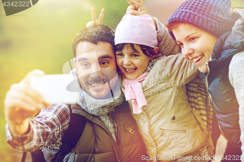 Image of family taking selfie with smartphone in woods