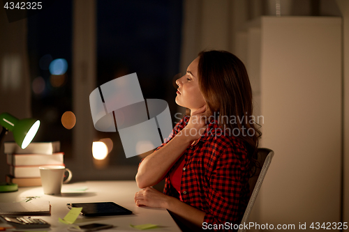 Image of tired student or woman touching neck at night home