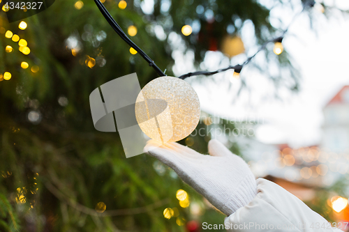 Image of close up of hand with christmas tree garland bulb