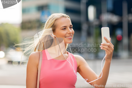 Image of happy young woman with smartphone and earphones