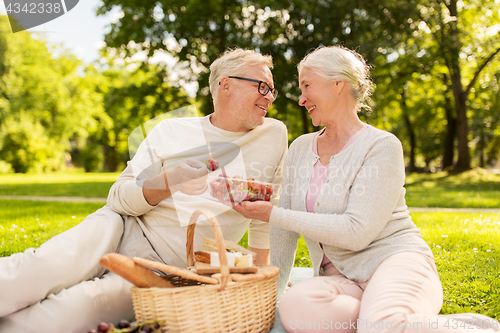 Image of senior couple with strawberries at picnic in park