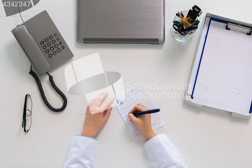 Image of doctor hands writing prescription at table