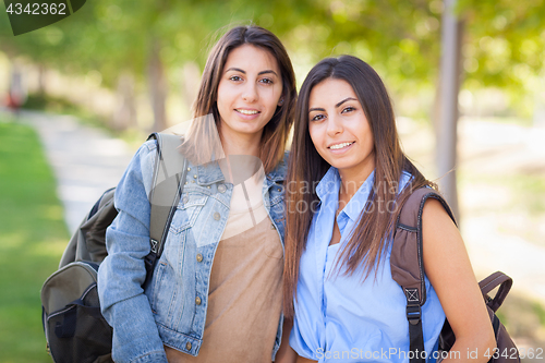 Image of Two Beautiful Young Ethnic Twin Sisters With Backpacks Walking O