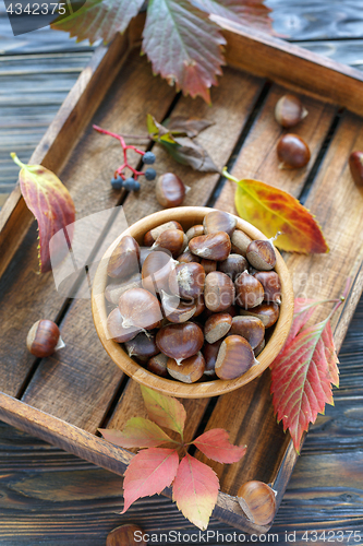 Image of Bowl with ripe chestnuts on a wooden box.