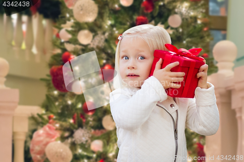 Image of Happy Young Girl Holding Gift Box In Front of Decorated Christma