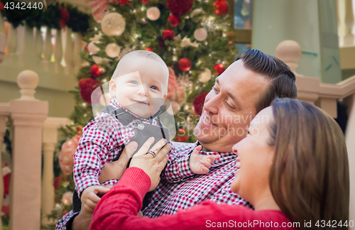 Image of Happy Young Parents with Baby In Front of Decorated Christmas Tr