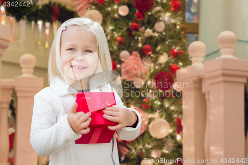 Image of Happy Young Girl Holding Gift Box In Front of Decorated Christma