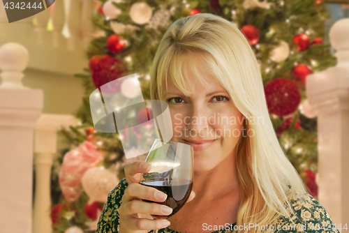 Image of Blond Woman with Wine Glass In Front of Decrated Christmas Tree.