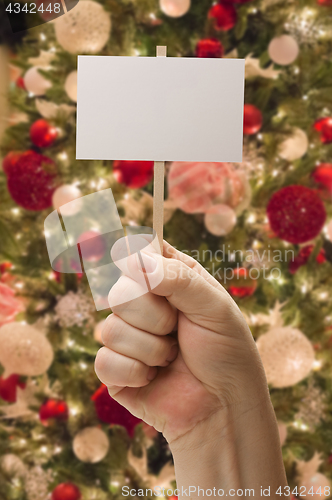 Image of Hand Holding Blank Card In Front of Decorated Christmas Tree.