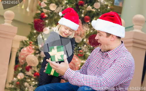 Image of Happy Young Girl and Father Wearing Santa Hats Opening Gift Box 