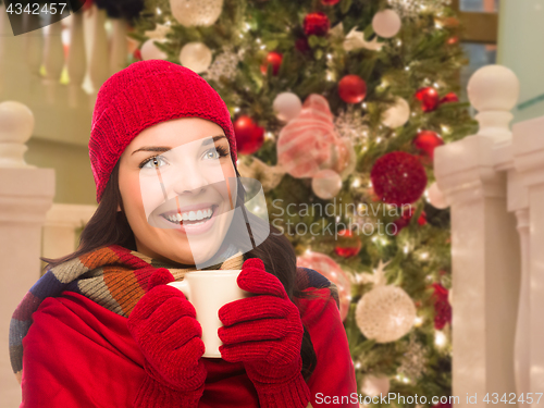 Image of Warmly Dressed Female With Mug In Front of Decorated Christmas T
