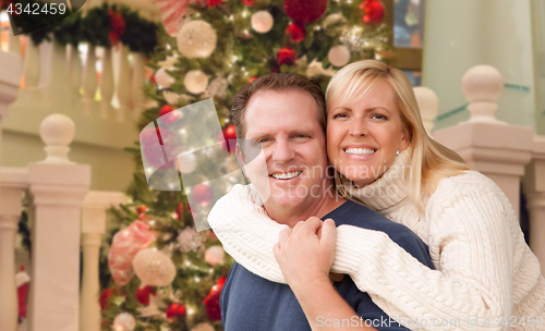 Image of Caucasian Couple Hugging In Front of Decorated Christmas Tree.