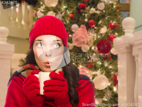 Image of Warmly Dressed Female With Mug In Front of Decorated Christmas T