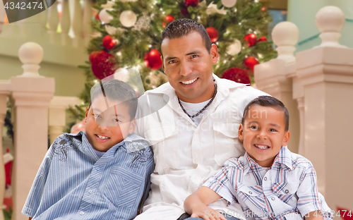 Image of Hispanic Young Father and Sons In Front of Decorated Christmas T