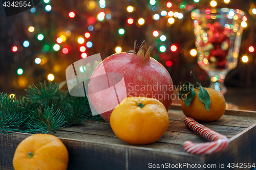 Image of Pomegranate, tangerines and Christmas lights.