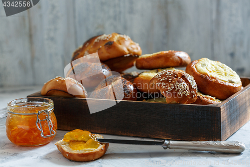 Image of Wooden tray with buns and a jar of orange jam.