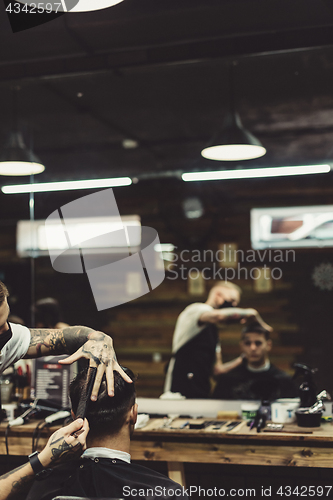 Image of Crop barber doing haircut for client