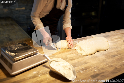 Image of baker portioning dough with bench cutter at bakery