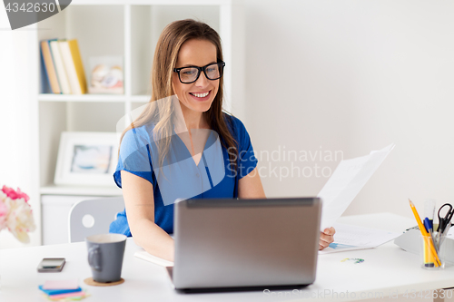 Image of happy woman with laptop working at home or office