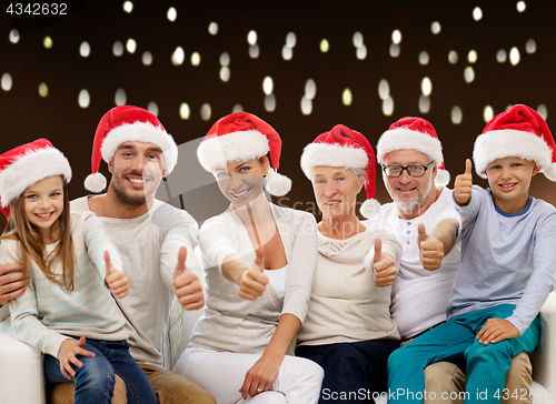 Image of family in christmas santa hats showing thumbs