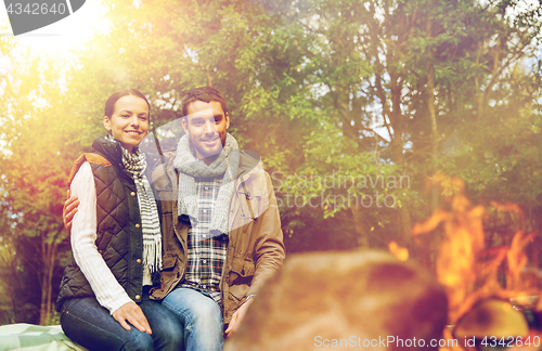 Image of happy couple sitting on bench near camp fire