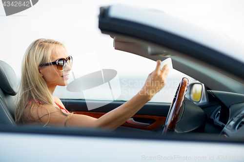 Image of woman in convertible car taking selfie