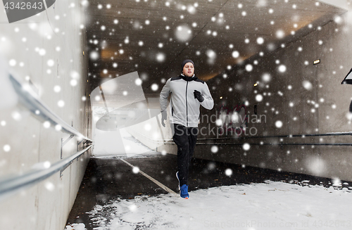 Image of man running along subway tunnel in winter