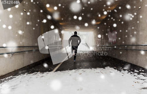 Image of man running along subway tunnel in winter