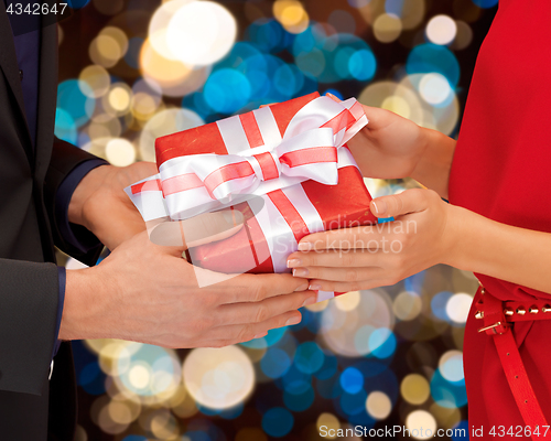 Image of close up of couple hands holding gift box