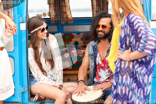 Image of happy hippie friends playing music in minivan