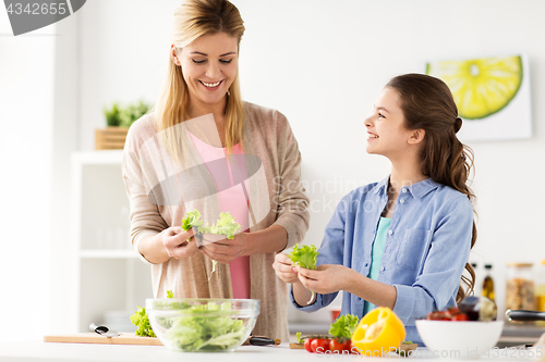 Image of happy family cooking salad at home kitchen