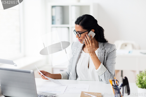 Image of businesswoman calling on smartphone at office