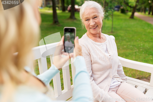 Image of daughter photographing senior mother by smartphone