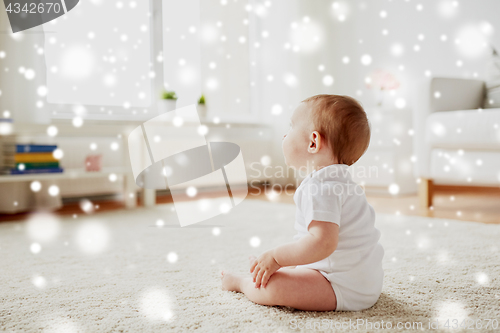 Image of happy baby boy or girl sitting on floor at home