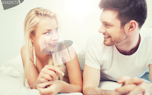 Image of happy couple lying in bed at home