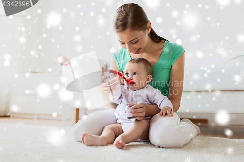 Image of mother with spoon feeding little baby at home