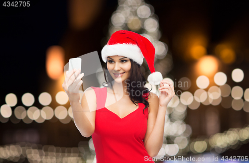 Image of woman in santa hat taking selfie by smartphone