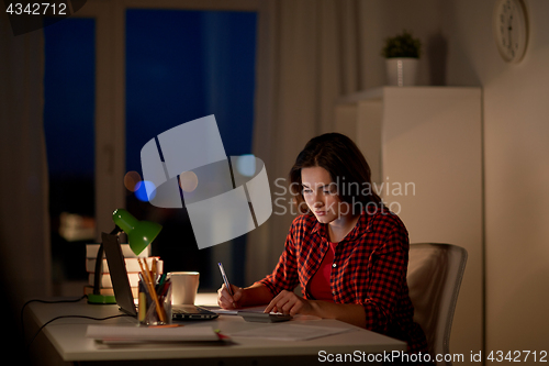 Image of student girl with notebook and calculator at home