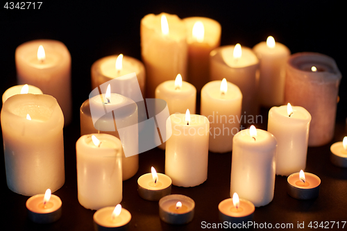 Image of candles burning in darkness over black background