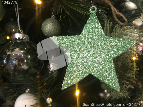 Image of Green glitter encrusted star hanging on a Christmas tree