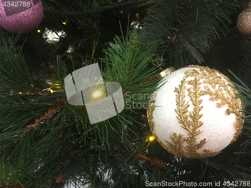 Image of Gold embellished Christmas decoration hanging on a green tree