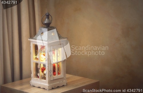 Image of Christmas baubles and golden fairy lights in lantern