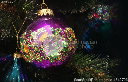 Image of Encrusted with crystals Christmas tree decorations hang on a tre