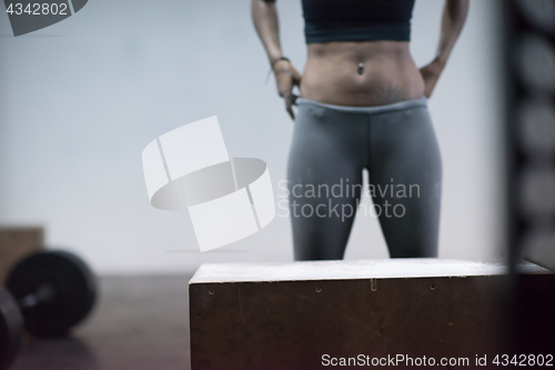 Image of black woman is performing box jumps at gym