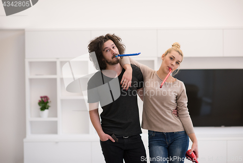 Image of couple in party hats blowing in whistle