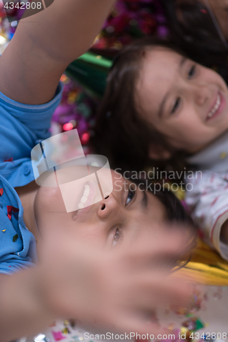 Image of kids  blowing confetti while lying on the floor