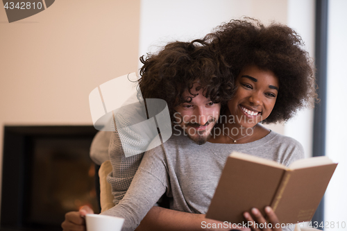 Image of multiethnic couple hugging in front of fireplace