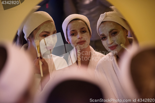 Image of women putting face masks in the bathroom