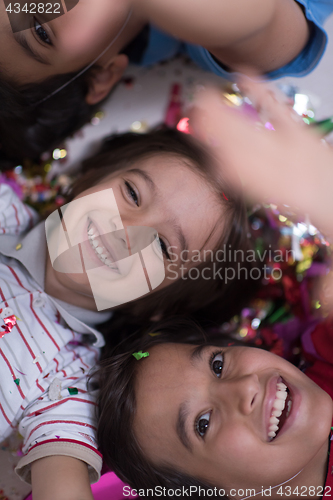 Image of kids  blowing confetti while lying on the floor