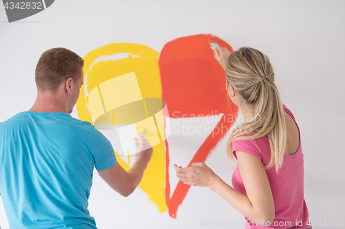 Image of couple are painting a heart on the wall